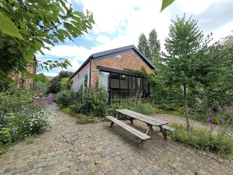 Exterior view of the brick studio building at 60, Grote Bosstraat with a picnic bench and garden.