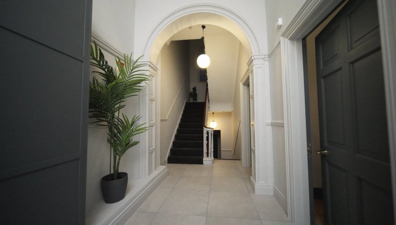 Entrance hallway at 62, Mount Street Lower, with a white archway, potted plant, and grand staircase.