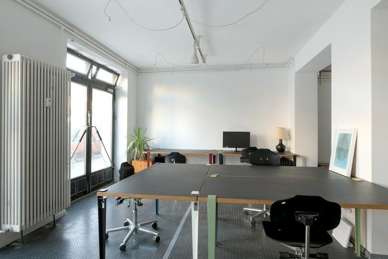 Natural light fills the shared workspace with black desks at 63, Stettiner Straße.