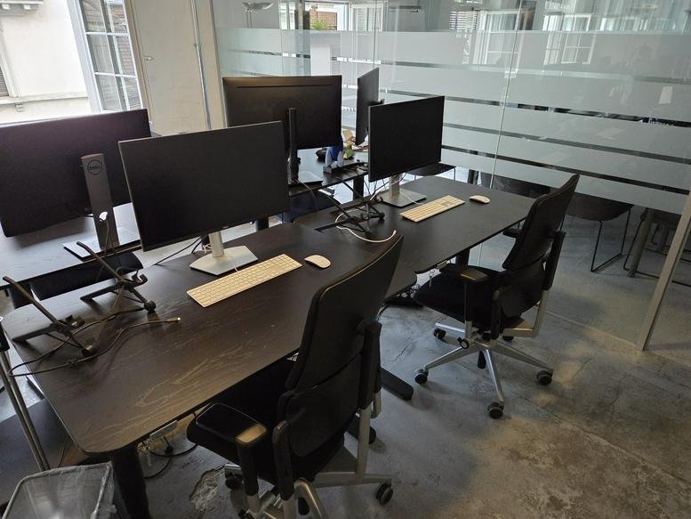 Open-plan workspace with multiple monitors and ergonomic black chairs at 65, Limmatstrasse.