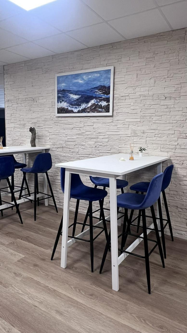 High-top white tables with blue velvet bar stools set against a textured wall.