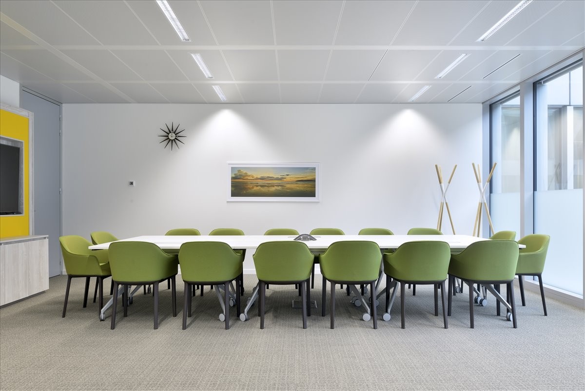 A professional boardroom at 7 – 15 Rue Gerda Taro with a long white table and lime green chairs.