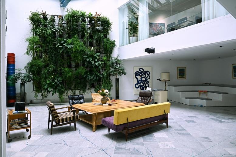 Spacious communal lounge at 7, Marokkanergasse, featuring a massive living plant wall and modern furniture.