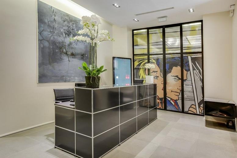 Modern lobby at 7 Rue Léo Delibes with a black paneled reception desk and comic book wall art.