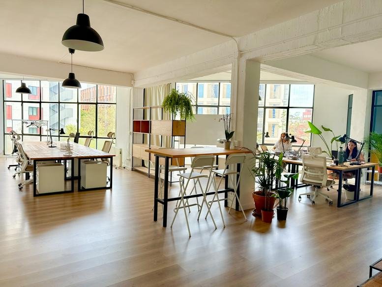 Spacious sunlit coworking area at 70, Carrer de Llull with wooden floors and tall windows.