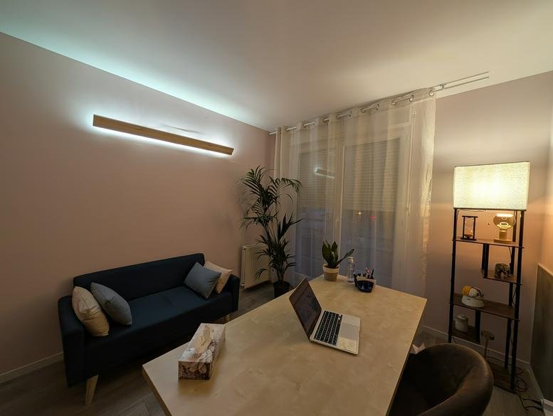 Warmly lit private office at 75, Rue Gambetta featuring a navy sofa, desk, and large floor lamp.