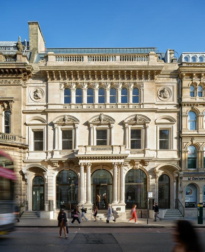 Ornate historic stone facade of the 81, Colmore Row, building under a clear blue sky.