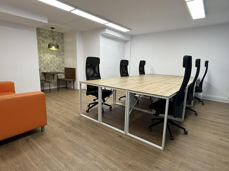 Spacious communal area with a long wooden desk and a bright orange chair.