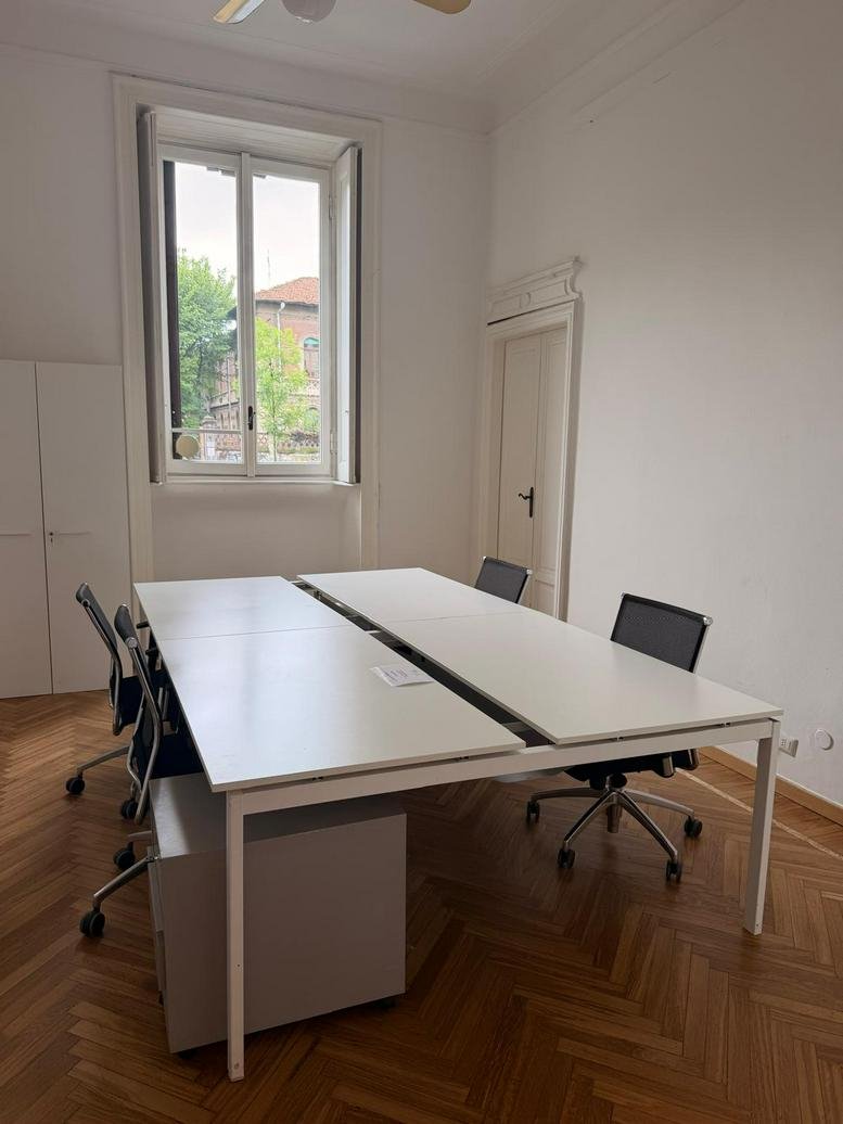 Professional four-person office suite at 9, Corso Plebisciti with herringbone wood floors and high ceilings.