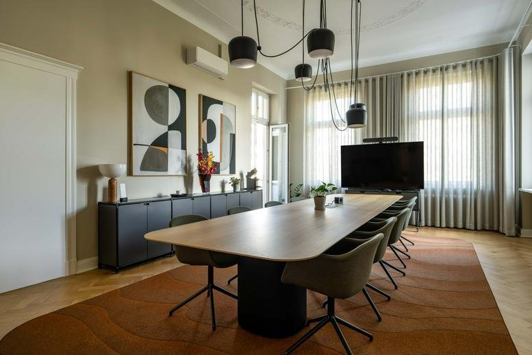 Large conference room with a long wooden table, modern lighting, and abstract wall art.