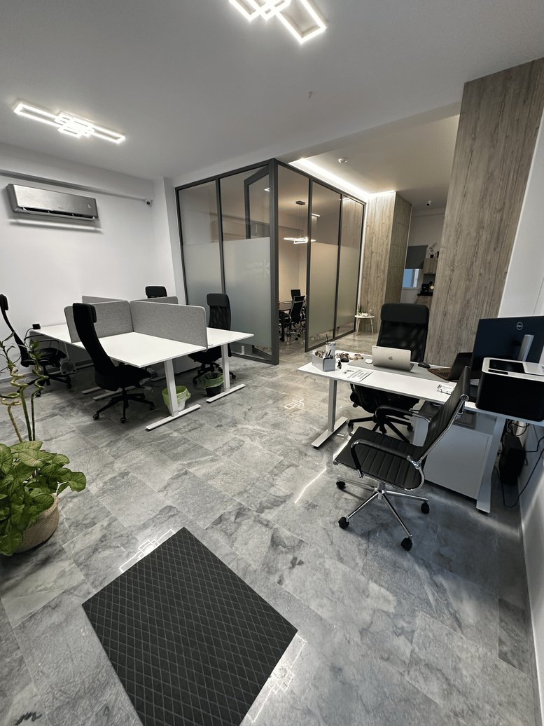 Spacious open-plan office at Akakion, 52 with white desks, ergonomic chairs, and a green plant.