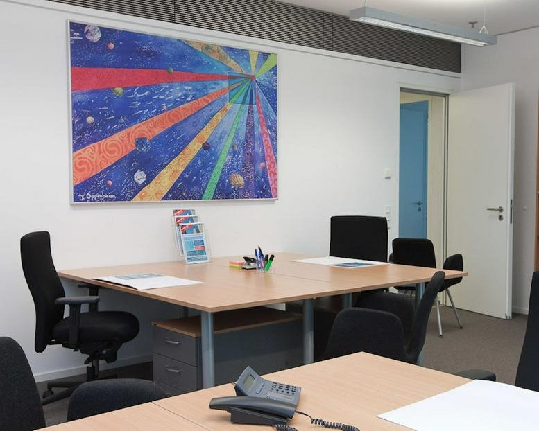 Spacious professional meeting room with a large light-wood table, black chairs, and a vibrant abstract painting.