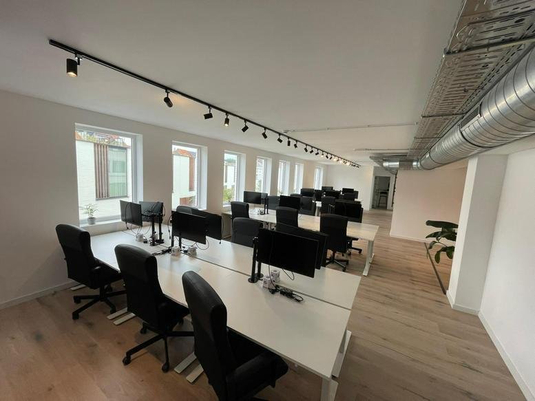 Spacious open-plan workspace at Antwerpsesteenweg 39,101/a with white desks and black chairs.