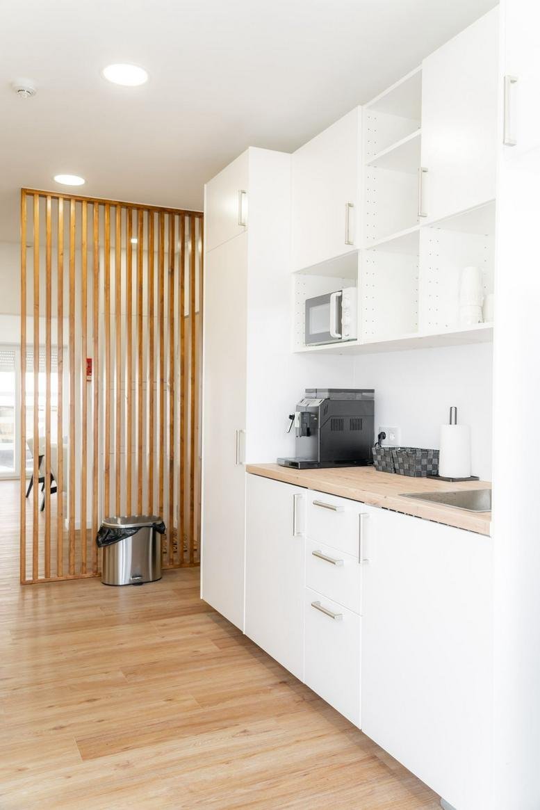 Bright communal kitchen area at Av. Costa Pinto 91, 1º with white cabinets and wood accents.