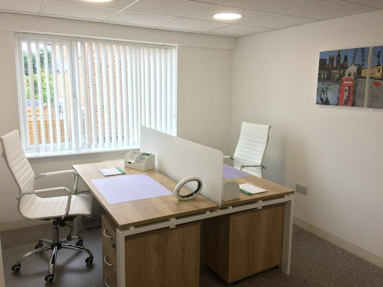 Bright two-person office at Battlefield Road with light wood desks and ergonomic white chairs.