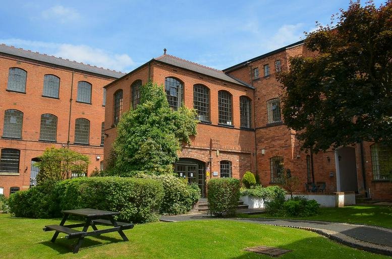 Exterior view of Bradford Court Business Centre with brick facade and greenery.