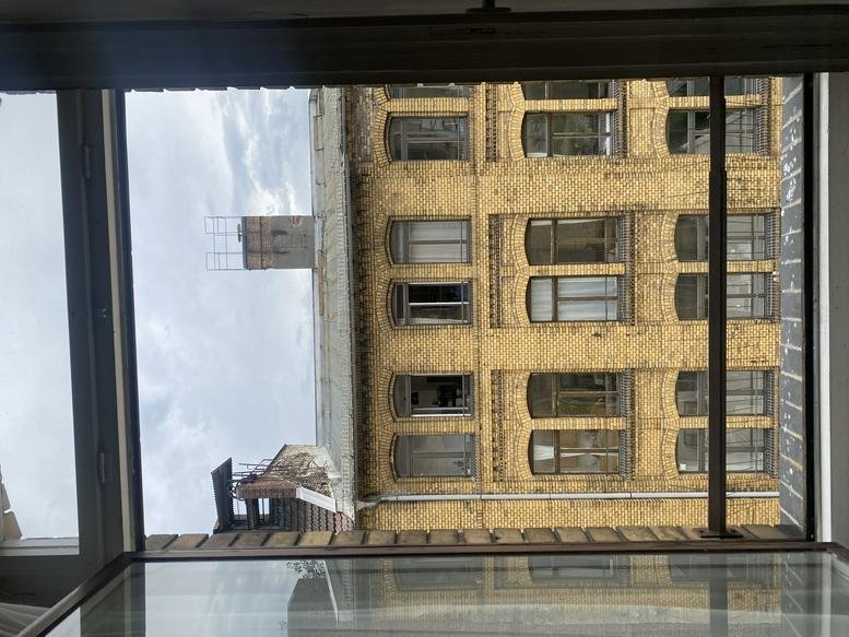 The classic yellow brick facade of the Brückenstraße building seen through a window.