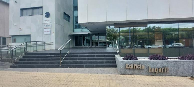 Exterior entrance of the modern Edificio Bogaris with wide steps and glass facade.