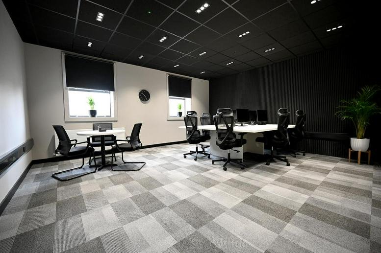 Spacious modern office at Carlyle House with a large white workstation, meeting table, and checkered grey carpet.