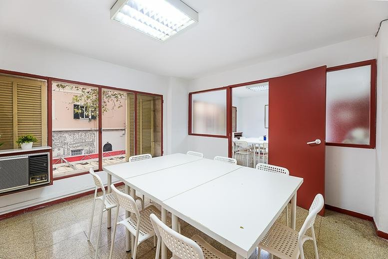 Meeting room at Carrer Guillem Costa featuring a white table, red sliding door, and courtyard views.