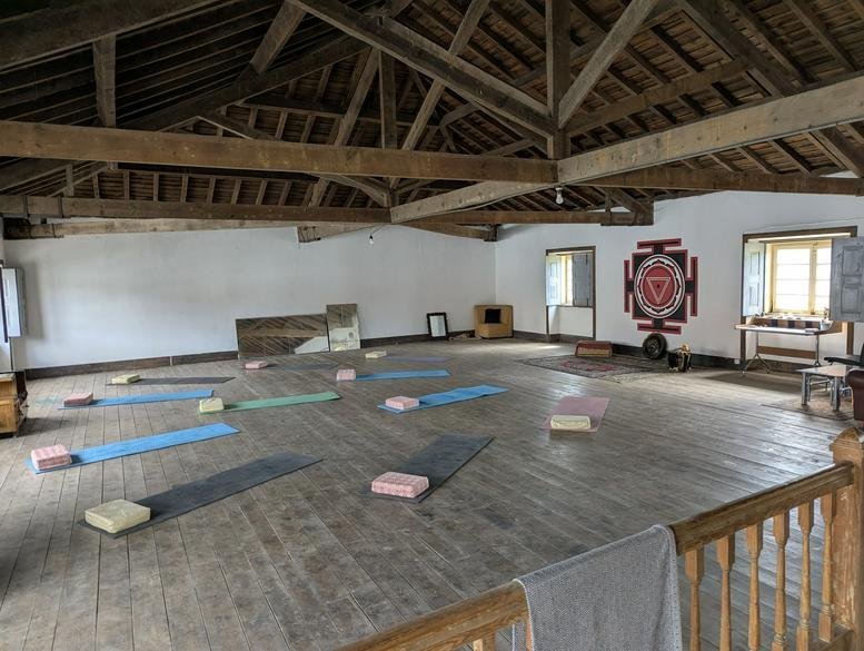 Spacious yoga studio at Casa Grande - Yoga Art residency featuring wooden floors, beams, and yoga mats.