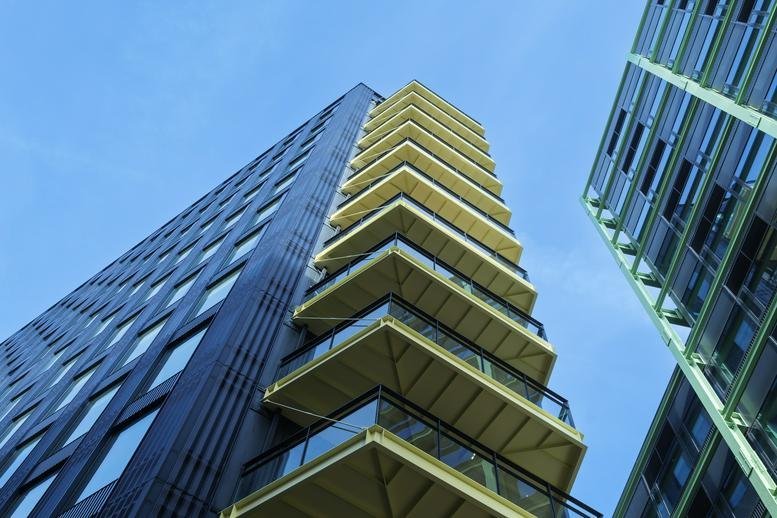 Low angle view looking up at the modern black and yellow facade of the Cheese Lane building.