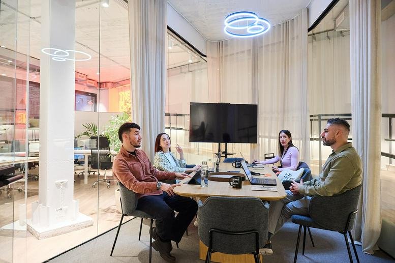 Meeting room at 1 Bis, Carrer de Colón with group of four people around a wooden table.