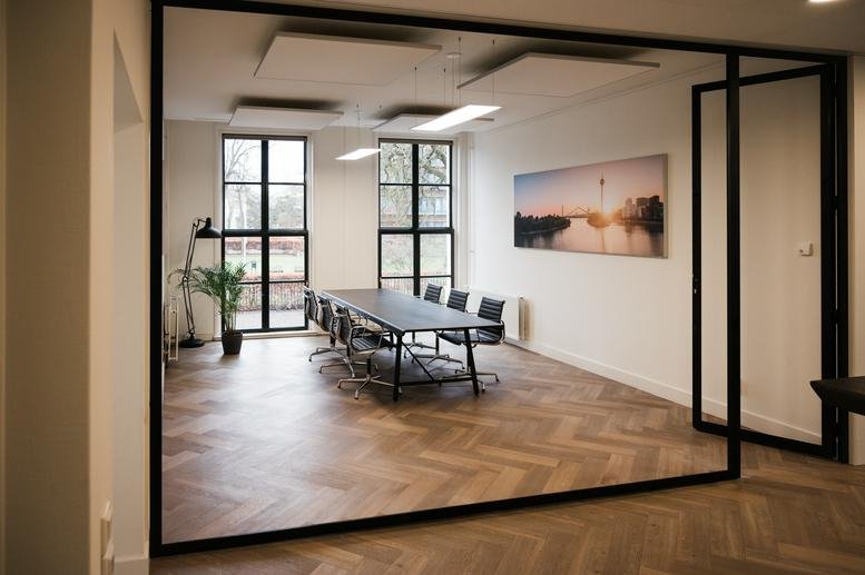 Bright conference room with glass walls and a large landscape painting.