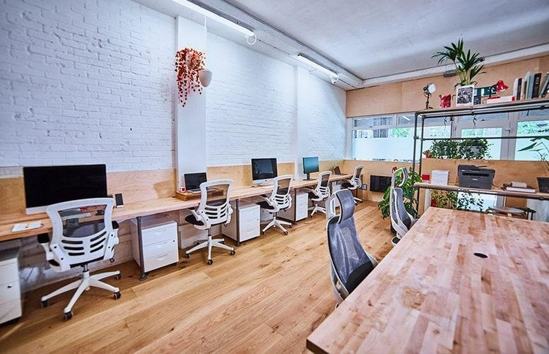 Spacious open-plan workspace at 109 Asylum Road with wooden desks and ergonomic white chairs.