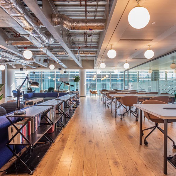 Spacious communal lounge with exposed ceilings, bookshelves, and diverse seating areas.