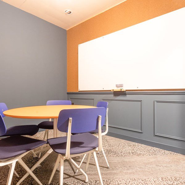 Expansive open-plan coworking space with rows of desks and industrial ceilings.