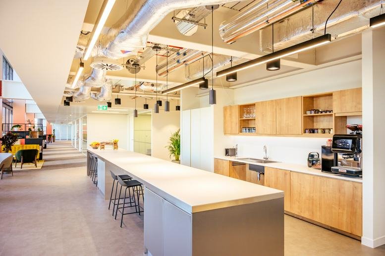 Spacious communal kitchen and dining area at 22 Bishopsgate, London with wood cabinetry and long island.