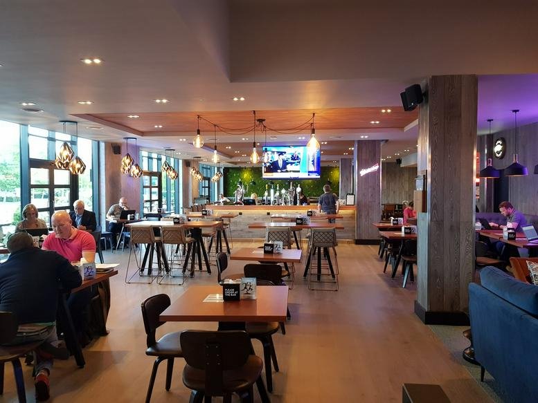 Spacious on-site cafe and bar area with warm lighting and various seating options.