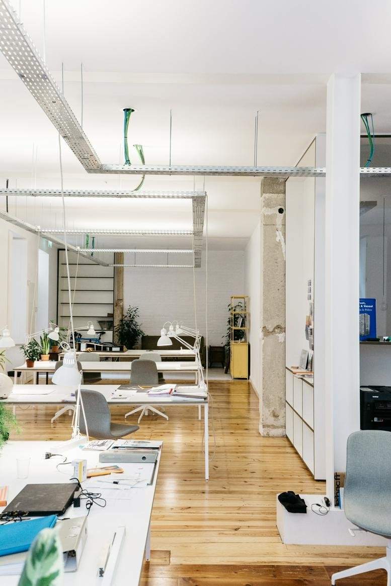 Modern office interior showing rows of desks with minimalist white and wood finishes.