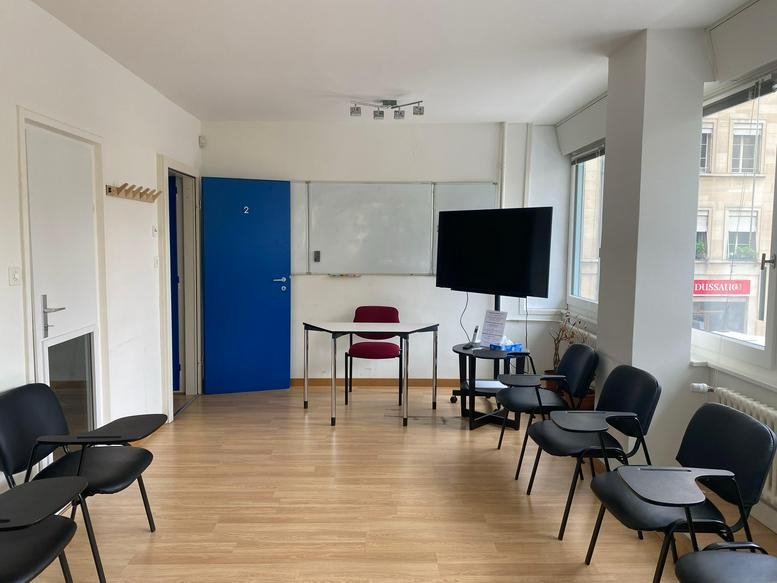 Classroom or meeting room at 3, Rue de Cornavin with a whiteboard, presentation screen, and rows of seating.