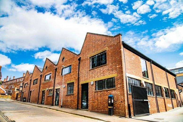 Red brick exterior of the sawtooth-roofed building at 34-38 Guildhall Road, Northampton.