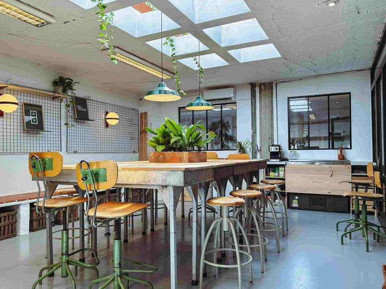 Wide-angle communal workspace at 4a, Carrer de Cristòfol Grober, Girona, with a large wooden table and skylights.