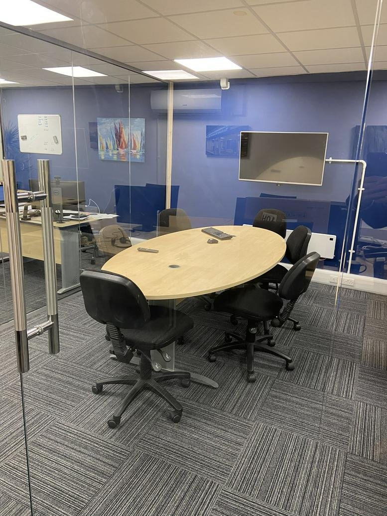 Meeting room at 5d Market Arcade, The Arcade, Bedford featuring an oval table and blue feature wall.