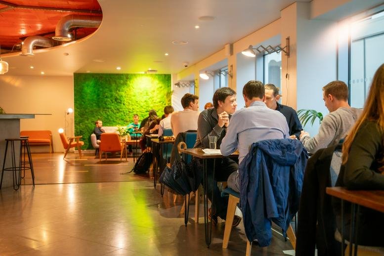 Spacious communal lounge at 69 Wilson Street, London, England featuring a green moss wall and cafe seating.