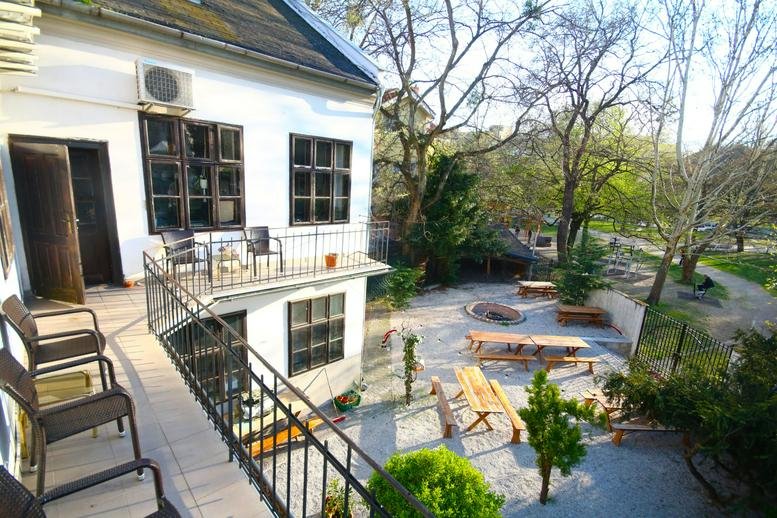 Exterior view of the white building at 6A, Sasinkova, 6 with a balcony and outdoor seating area.