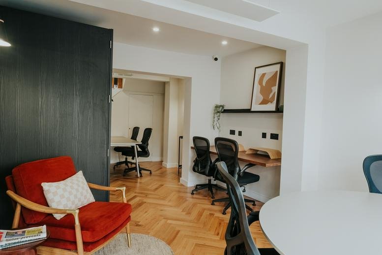 Spacious interior of 8 Freckleton Street, Preston featuring a red armchair and wooden herringbone floors.