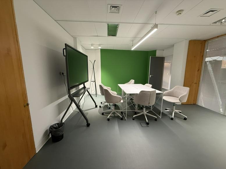 Bright meeting room featuring a green accent wall and a large digital screen.