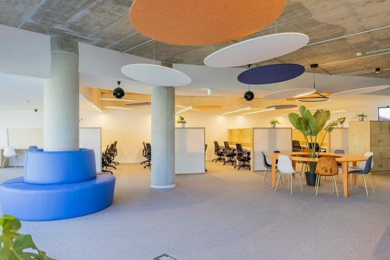 Spacious communal lounge at Av. da República 1363 with colourful acoustic ceiling discs and blue seating.