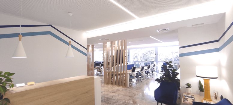 Reception area at Edificio Regina featuring a wooden desk, pendant lights, and blue geometric wall patterns.