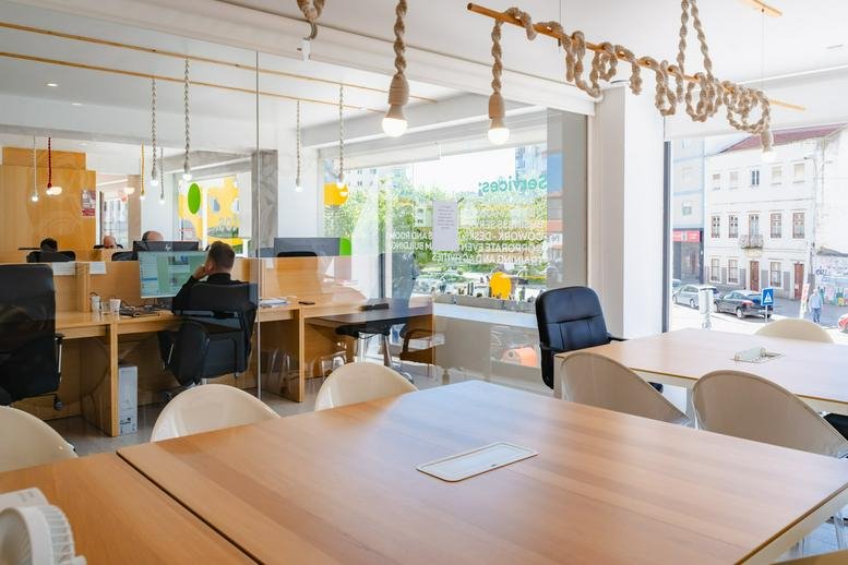 Spacious communal coworking area with large wooden tables and modern rope lighting.