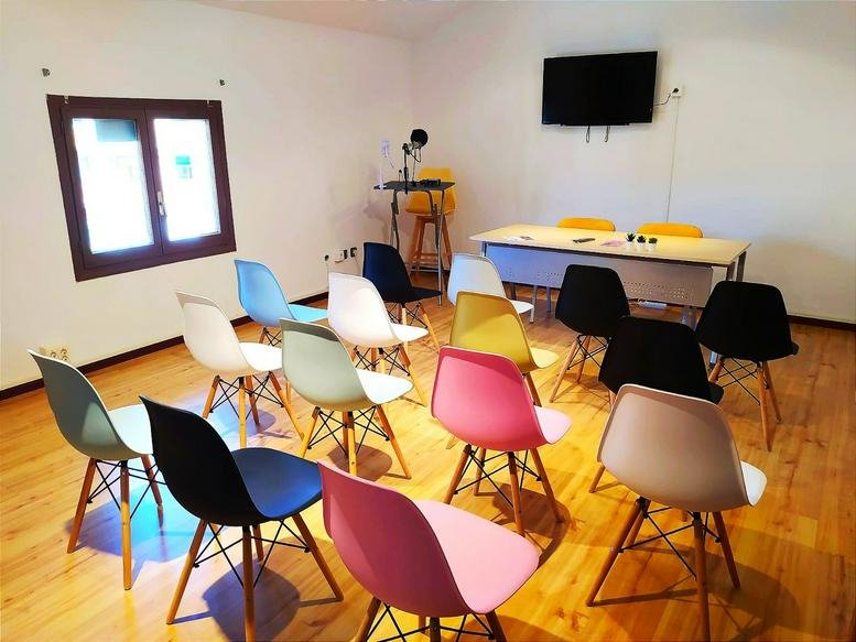 Meeting room at Avenida Acueducto, 13 featuring vibrant multi-colored chairs and a wall-mounted TV.