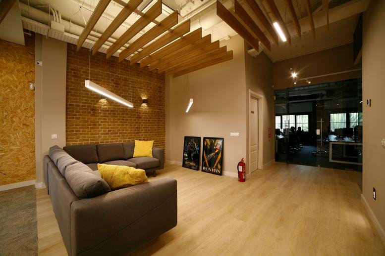Warm breakout lounge at Avenue Matas Verdes 2E with a gray sectional and wooden slat ceiling.