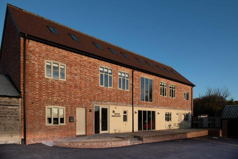 Exterior brick facade of the Builder’s Yard, Hinton Saint Mary, Dorset with modern glazing and wooden decking.