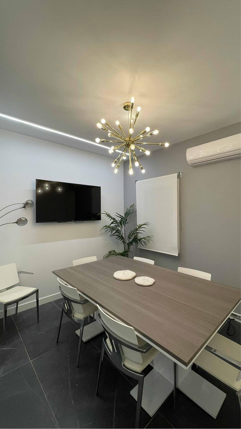 Boardroom at Calle Claudio Coello 76 with a large wood table and a designer starburst chandelier.