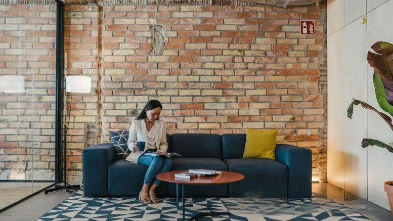 Exposed brick lounge area at Calle Comte Borrell 62, Sant Antoni, Barcelona featuring a blue sofa and rug.